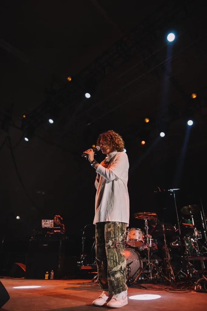 Full-length live performance on stage with drums and spotlights.
