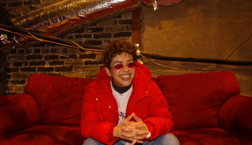 Portrait on a red couch in an industrial-style room with exposed brick. Photo: Audrey Smith.