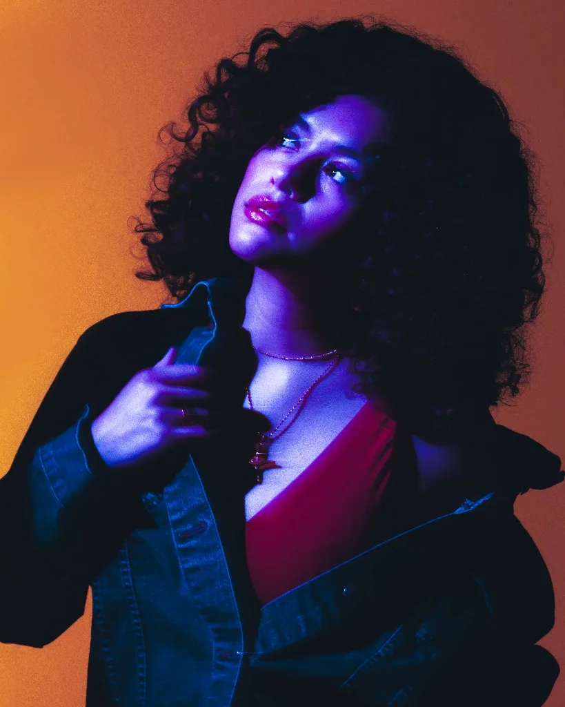 Moody portrait in a denim jacket with dramatic blue and orange lighting.